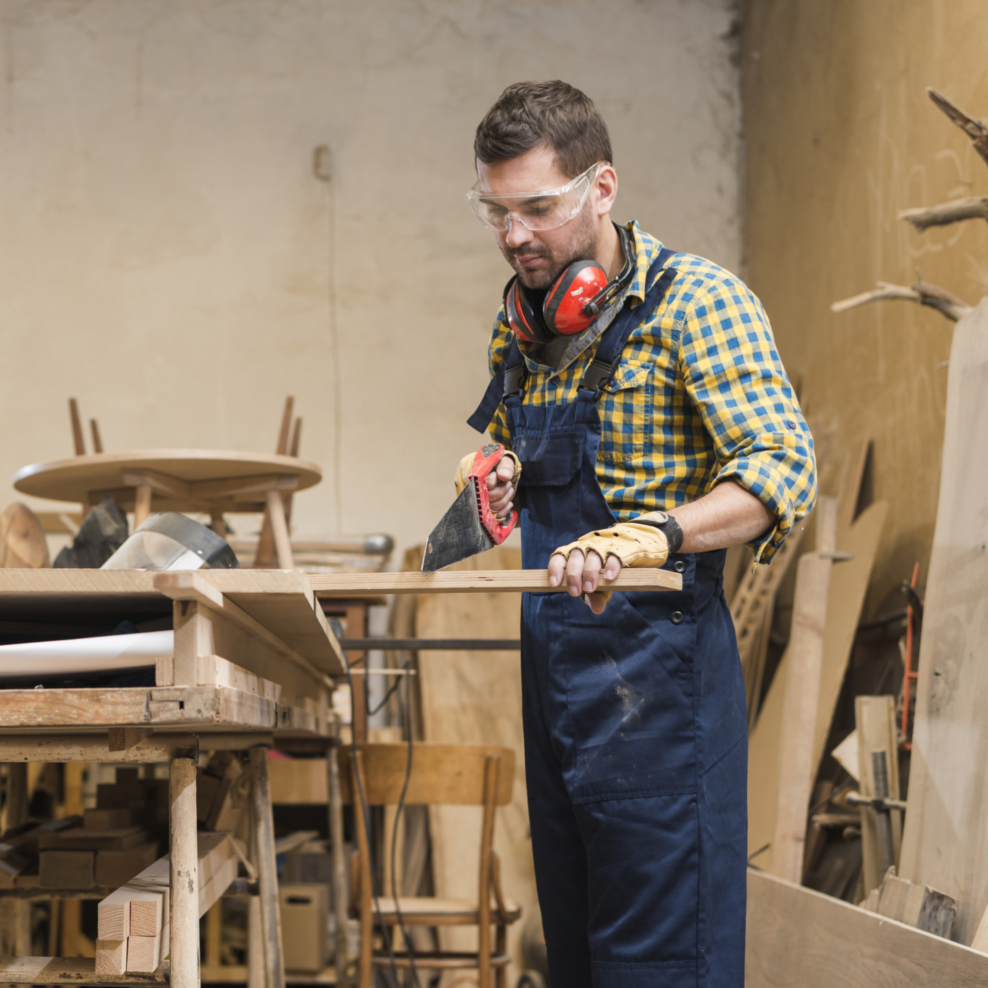professional-carpenter-cutting-wooden-plank-with-handsaw-workshop